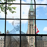 Silhouette of Louis Riel with Parliament Hill in the background.