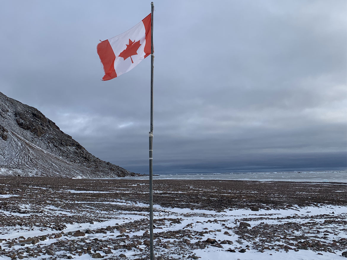 Canadian flag on a pole on a frozen landscape.