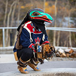 Danseur portant des vêtements traditionnels et un masque de corbeau.