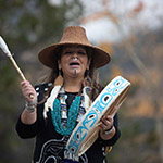 Marilyn, vêtue d'une tenue de cérémonie traditionnelle, joue du tambour et chante.