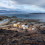 A group of cabins and tents located on a rocky formation along the shore of the Arctic ocean.