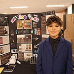 A participant standing in front of their project board.