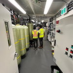 Two people wearing safety vests walking through the treatment plant.