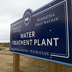 Road sign that says "Michisaagiig of Rice Lake, Hiawatha First Nation, Nibi Nimaadiziwin/Water Treatment Plant, Water is Life".