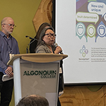 Lucy Grey, Dr. Pierre Ayotte and Dr. Barak presenting onstage with a slideshow.