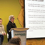 Professor. Ostertag presenting onstage with a slideshow.