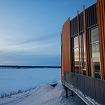 Un bâtiment fait face à une large étendue de neige au crépuscule.