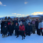 ARENA participants standing outside in the snow with a mountain range in the background.