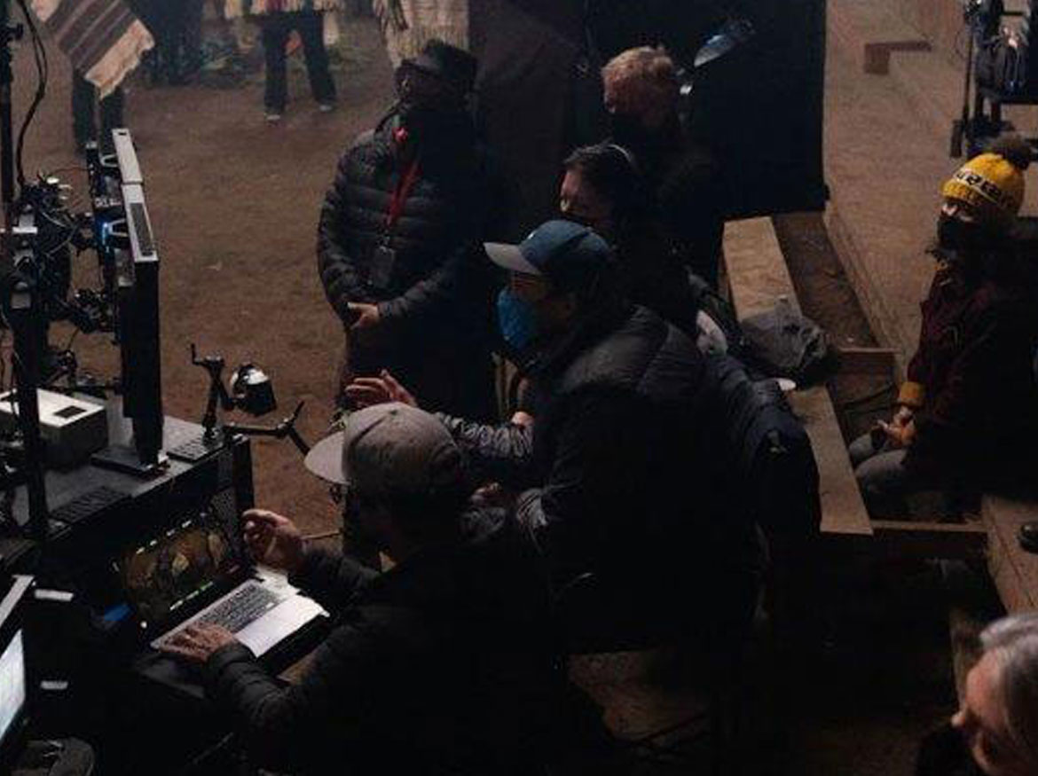 Cast and crew watching video screens on set.
