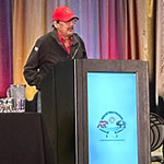 Clarence Mason standing behind a podium onstage at the signing ceremony.