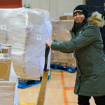 A Harvest Manitoba worker pushing a pallet carrying boxes of food.