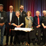 Partenaires et membres des communautés des Premières Nations et des Inuit en tenue traditionnelle devant le protocole d’entente.