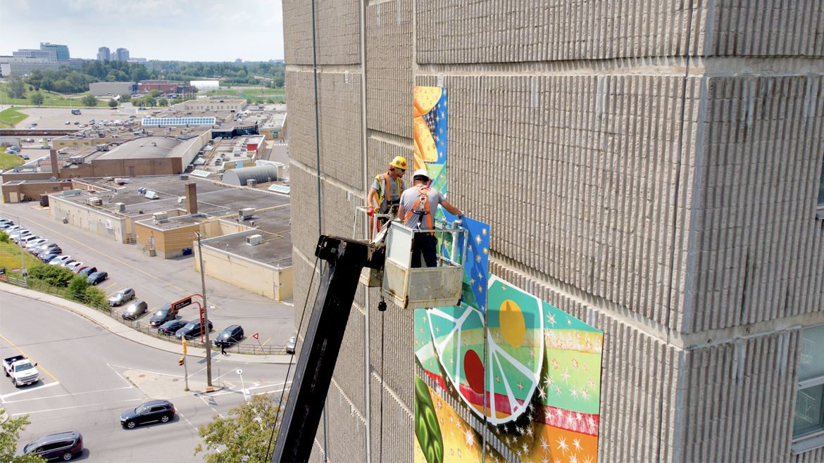 Hommes sur une grue installant des panneaux muraux sur le côté du bâtiment