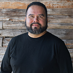 Keith McCrady, smiling in front of a wood-paneled wall.