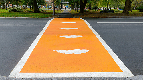 Crosswalk painted orange with white feathers