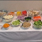 A table with various bowls of salad ingredients.