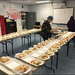 Two people preparing takeout containers of food.