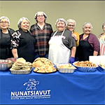 A group of breakfast program volunteers standing behind a table of food.