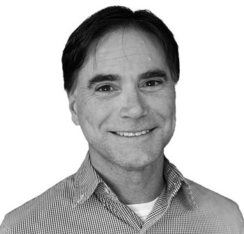 Photo en noir et blanc d'un homme souriant.