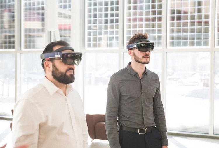 Two men in business attire wear virtual reality googles to experience a virtual version of the Giant Mine site.