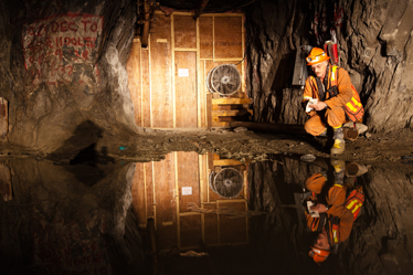 A mine worker examines an underground pool of water at the Giant Mine site.