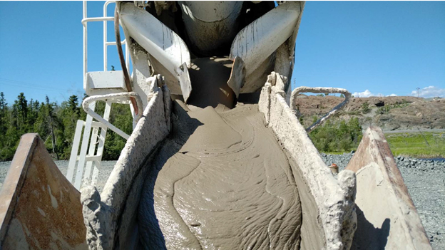 This picture shows a grey, cement-like substance flowing down from a truck into a trough so it can be delivered into the underground.